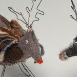 Two reindeer toys made from scrape material and wire on a white background.
