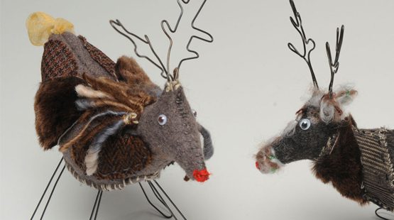 Two reindeer toys made from scrape material and wire on a white background.