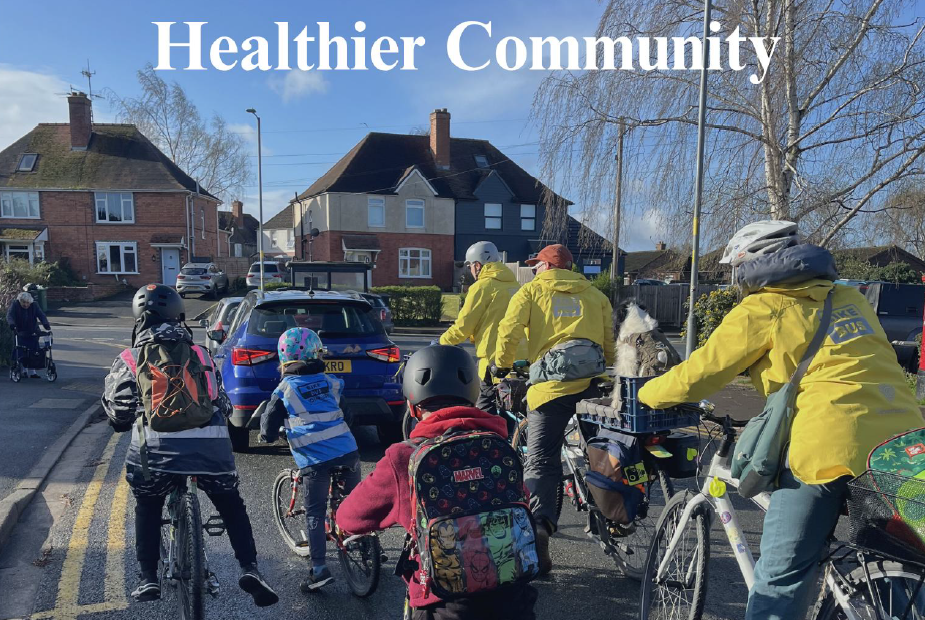 rear view of children, adults and a dog cycling on a residential road
